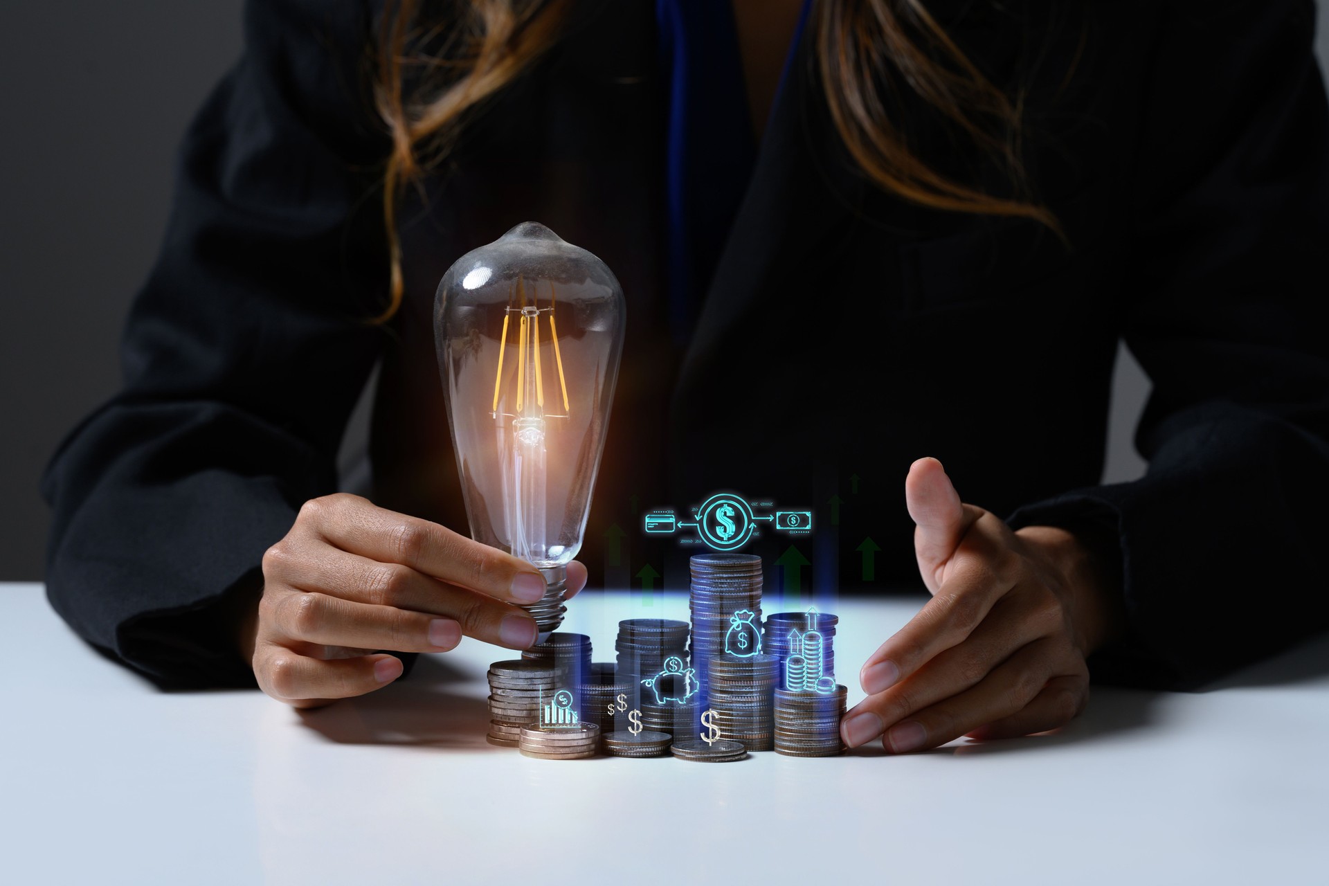 Businesswoman hand holding glowing light bulb on coin stacking. Saving money and financial growth concept